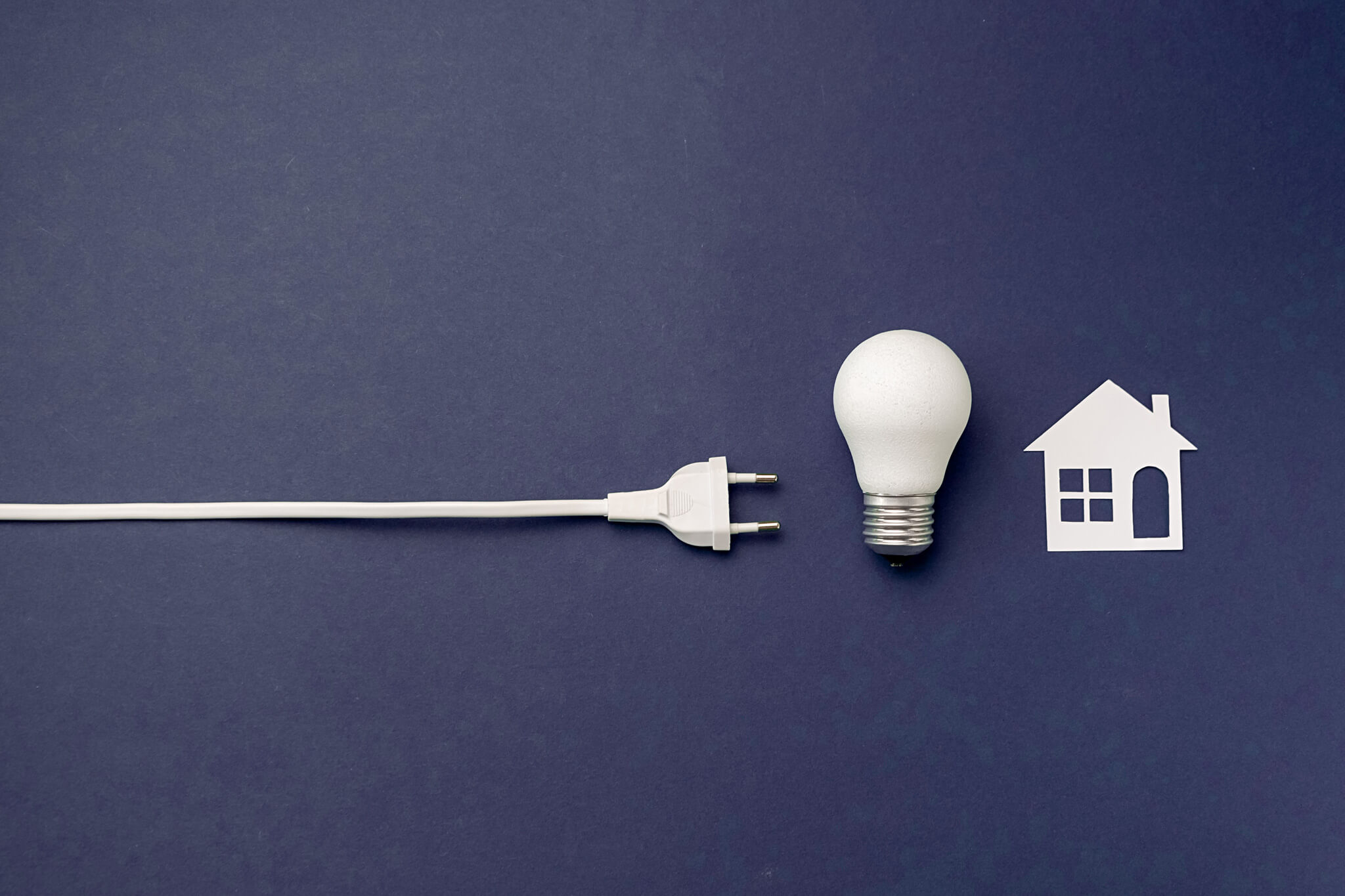 Grafica bianca su sfondo blu di una presa elettrica, una lampadina e disegno di una casa